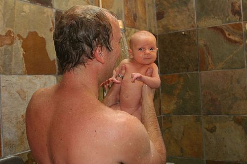 Father with baby in shower by Joel Tornatore